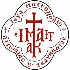 Red Greek Orthodox cross with Greek text in a four-lobed border emblem.